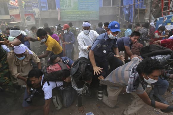 Bangladeshi rescue workers and media fall on top of each other in a stampede after the crowd panic when someone shouted a section of building might collapse, at the site of a building that collapsed Wednesday in Savar, near Dhaka, Bangladesh.