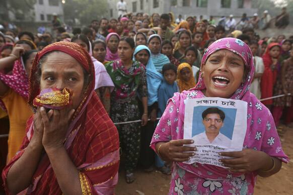 A Bangladeshi woman weeps as she holds a picture of her and her missing husband as she waits at the site of a building that collapsed Wednesday in Savar, near Dhaka, Bangladesh.