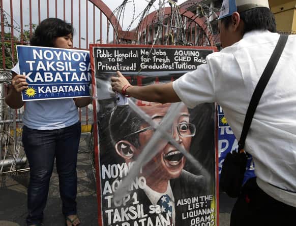 A student spray-paints a mock magazine cover photo of Philippine President Benigno Aquino III heralding him as one of 100 Most Influential Leaders of the World during a rally near the Presidential Palace in Manila, Philippines.