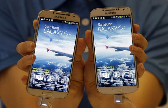 A model shows Samsung Electronics Co.`s latest Galaxy S4 smartphones during its unveiling ceremony in Seoul, South Korea.