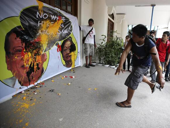 A protester throws paint at the tarpaulin poster of President Benigno Aquino III and Labor Secretary Rosalinda Baldoz during a rally at the Labor Department in Manila, Philippines to protest recent statement by the Government of not granting any wage increase for next week`s Labor Day celebration.
