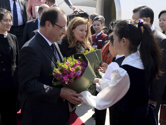 French President Francois Hollande, left, and his partner Valerie Trierweiler, center, are greeted by children as they arrive at the Beijing Capital International Airport.