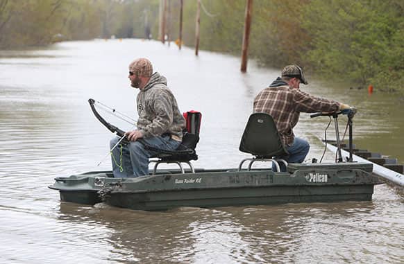 Kevin Eastman, left, prepares his bow for fishing on the flooded Missouri Highway 94 just outside of West Alton, Mo., as his brother, Sean Eastman, right, both of Ferguson, Mo., fights to keep the strong current from pressing their boat against the guardrail.