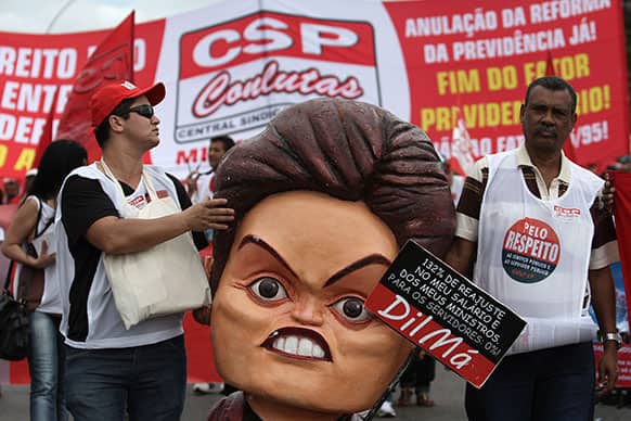 Demonstrators carry a puppet of Brazil`s President Dilma Rousseff during a protest by labor unions in Brasilia, Brazil.
