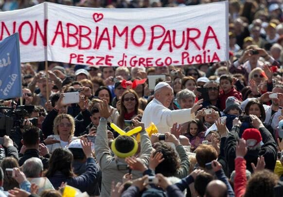 Pope Francis waves to faithful as he is driven through the crowd in his popemobile during his weekly general audience in St. Peter Square at the Vatican.