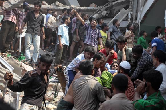 A woman, facing the camera on right, who was trapped in a collapsed eight-story building housing several garment factories, is recued in Savar, near Dhaka, Bangladesh.