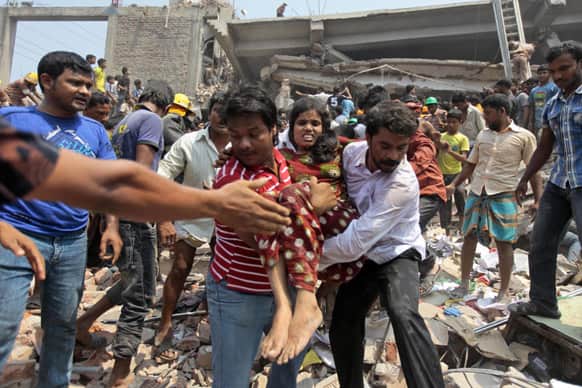 Rescuers assist an injured woman after an eight-story building housing several garment factories collapsed in Savar, near Dhaka, Bangladesh.