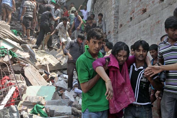 Rescuers assist an injured woman after an eight-story building housing several garment factories collapsed in Savar, near Dhaka, Bangladesh.