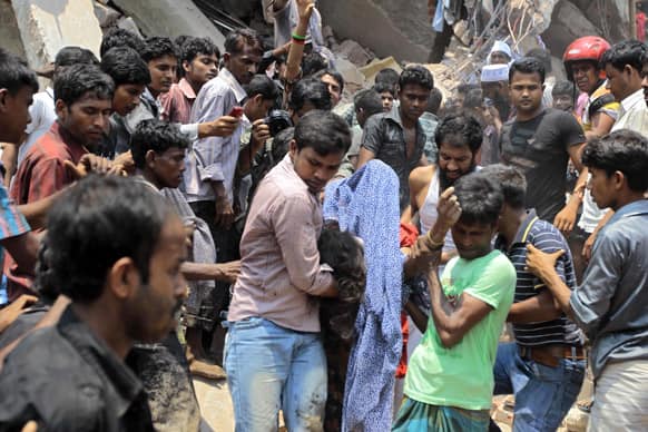 Rescue workers carry a victim`s body after an eight-story building housing several garment factories collapsed in Savar, near Dhaka, Bangladesh.