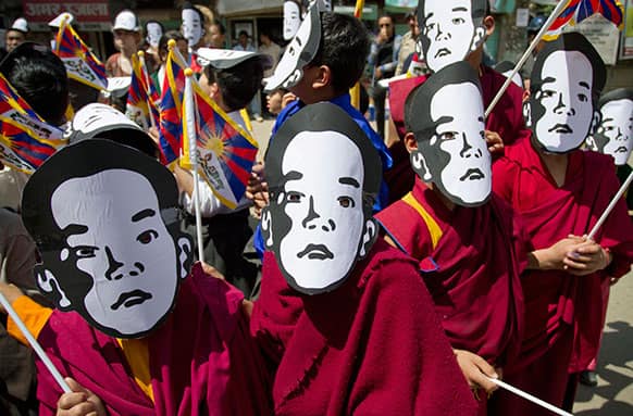 Young exile Tibetan Buddhist monks carry Tibetan flags and wear masks of the Tibetan Buddhist leader Panchen Lama during a protest gathering demanding his release the day before his birthday in Dharmsala.