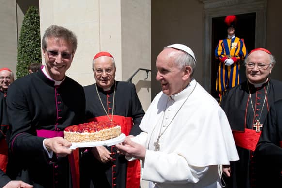 This photo provided by the Vatican paper L` Osservatore Romano, Pope Francis is presented with a cake by the Swiss Guards chaplain Alain de Raemy on the occasion of a celebration for the feast of Saint George, his namesake, at the Vatican.