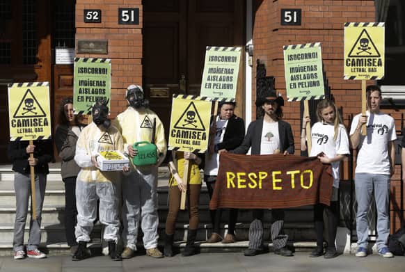 Environmental activists, some wearing gas masks and holding placards, demonstrate outside Peru`s embassy in London.