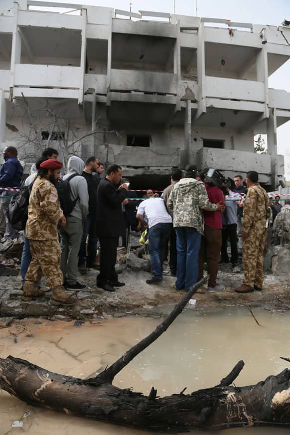 Security personnel and journalists inspect the site of a car bomb that targeted the French embassy wounding two French guards and causing extensive material damage in Tripoli, Libya.