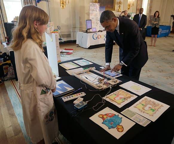 President Barack Obama uses a paint-bot, a drawing robot that paints with watercolors, built by Sylvia Todd, left, from Auburn, Calif., during a tour of the White House Science Fair.