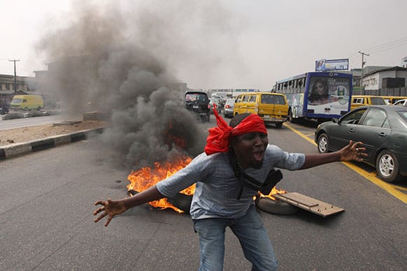 An unidentified man shouts slogans near burning tyres during a protest on a major road junction in the commercial capital of Lagos, Nigeria.