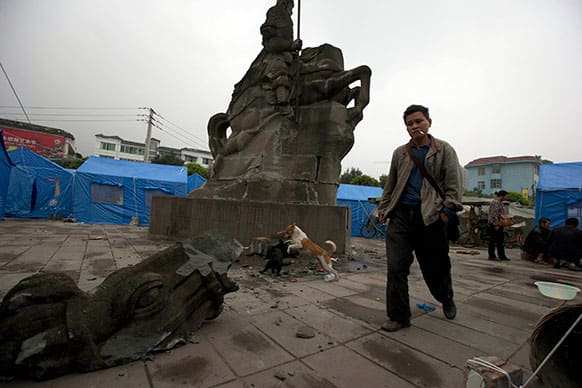 A man walks past a statue of a horseman damaged by Saturday`s earthquake in Lushan county, in southwestern China`s Sichuan province.