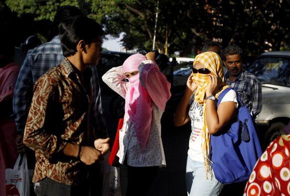Young women cover their faces as they walk past the site of a demonstration organized by All India Mahila Samskarika Sanghatana, a women`s organization, against the rape and torture of a 5-year-old girl in Delhi, during a protest in Bangalore.