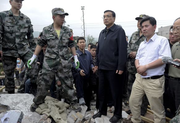 Chinese Premier Li Keqiang, center, is escorted by officials and rescuers as he visits a site damaged by an earthquake at a village in Lushan county, Ya`an, southwest China`s Sichuan province.