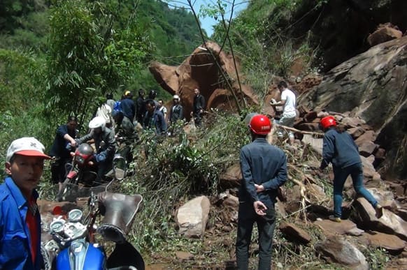 People try to get across a road blocked by a landslide following a powerful earthquake in Lushan county in southwest China`s Sichuan province.