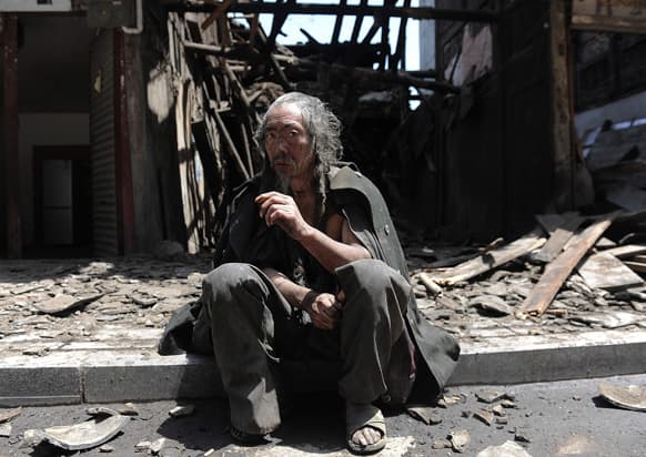 A man sits in front of the houses destroyed by an earthquake which hit Lushan county in Ya`an in southwest China`s Sichuan province.