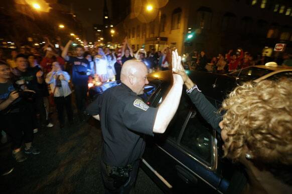 A police officer and a woman react to news of the arrest of one of the Boston Marathon bombing suspects.