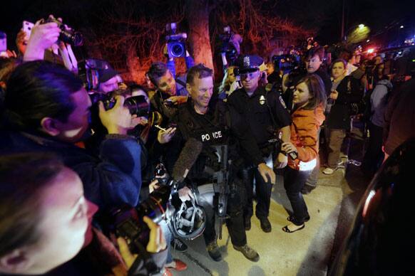 A gathering of people including the media gather around a police officer as he leaves the scene after the arrest of a suspect of the Boston Marathon bombings in Watertown.
