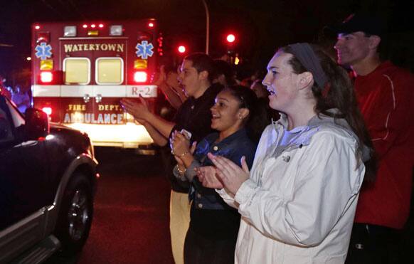 A gathering of people applaud as first responders leave the scene after the arrest of a suspect of the Boston Marathon bombings in Watertown, Mass.