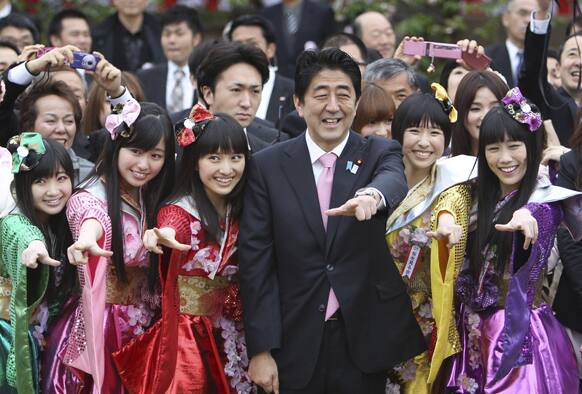 Japan`s Prime Minister Shinzo Abe, third right, strikes a pose with members of Japan`s girls pop unit