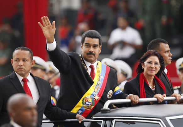Venezuela`s President Nicolas Maduro waves from a vehicle, next to his companion Cilia Flores, during a military ceremony recognizing him as Commander-in-chief to the military at the Paseo Los Proceres in Caracas, Venezuela.