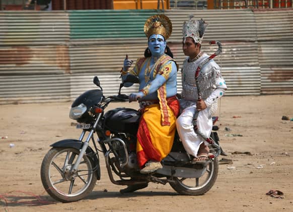 Men dressed as Hindu God Rama and Arjun sit on a motorcycle as they arrive to participate in a religious procession to mark ‘Ram Navami’ festival in New Delhi.