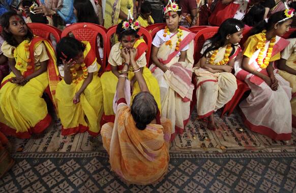 An elderly Hindu devotee worships a young girl dressed as
