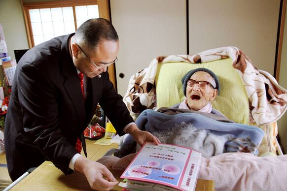Kyotango city mayor Yasushi Nakayama, left, hands out a binder full of birthday messages to Jiroemon Kimura at his home in Tango, Kyoto Prefecture, western Japan. Kimura who turned 116 on Friday, became the oldest living man last December.
