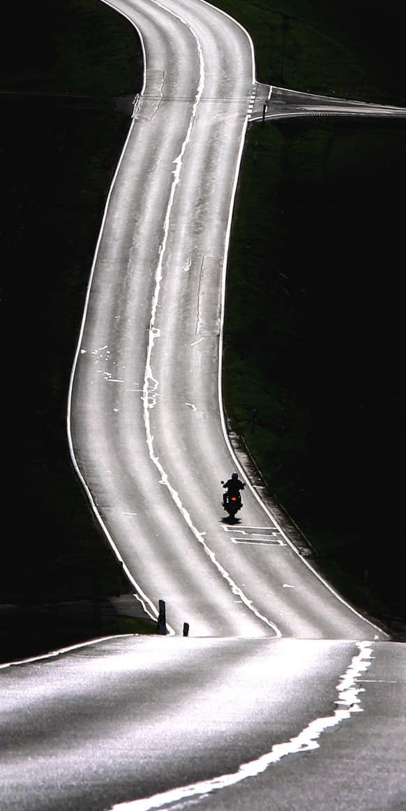 A motorcyclist rides along the street which is illuminated by the sun near Remlingen, Germany.