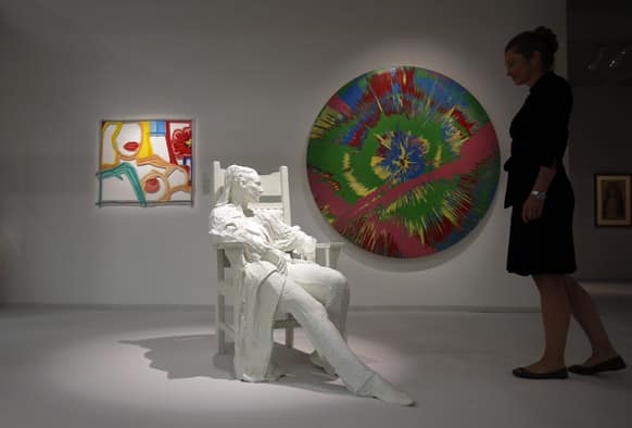 A visitor watches the sculpture `Woman in Armchair` made of bronze with white patina by US artist George Segal at the ART COLOGNE fair in Cologne, Germany.
