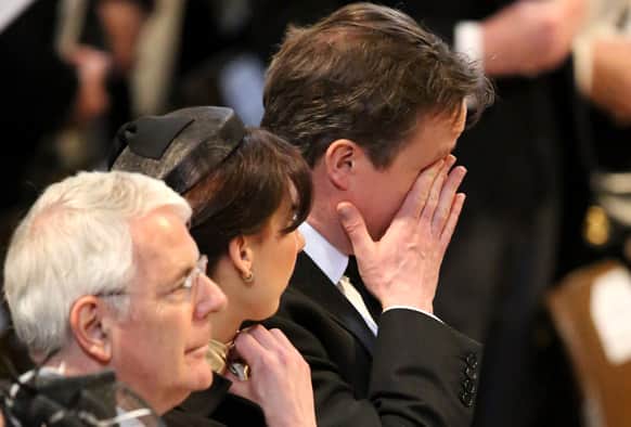 Britain`s Prime Minister David Cameron wipes his face next to his wife Samantha Cameron and former British Prime Minister John Major as they attend during the ceremonial funeral of former British Prime Minister Margaret Thatcher at St Paul`s Cathedral in London.