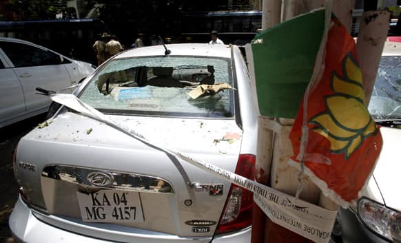 A partly torn poster of Bharatiya Janata Party (BJP) hangs on an electric pole next to a car, damaged in an explosion in a residential neighborhood near the BJP office, in Bangalore.
