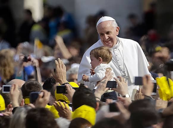 Pope Francis kisses a child as he arrives in St. Peter`s Square at the Vatican for his weekly general audience.