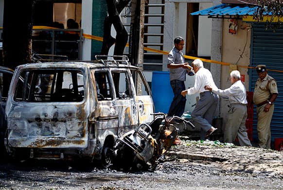 Elderly people walk past charred vehicles as they are taken to a safer place after an explosion in a residential neighborhood near the office of India`s main opposition Bharatiya Janata Party in Bangalore.