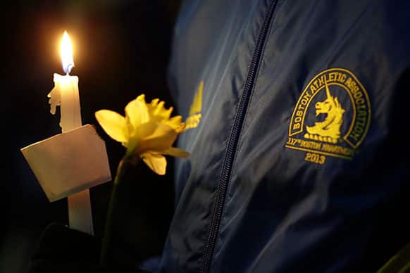 Lizzie Lee, 56, of Lynwood, Wash., who was participating in her first Boston Marathon and 11th overall, holds a candle and a flower at Boston Common during a vigil for the victims of the Boston Marathon explosions.