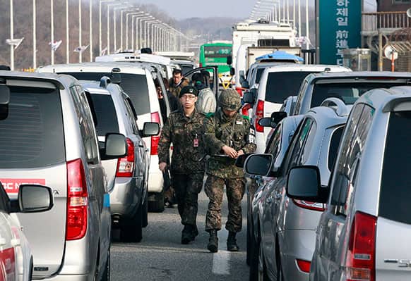 South Korean army soldiers check the media identities as they wait to leave to the customs, immigration and quarantine office, at Unification Bridge in Paju, South Korea, near the border village of Panmunjom.