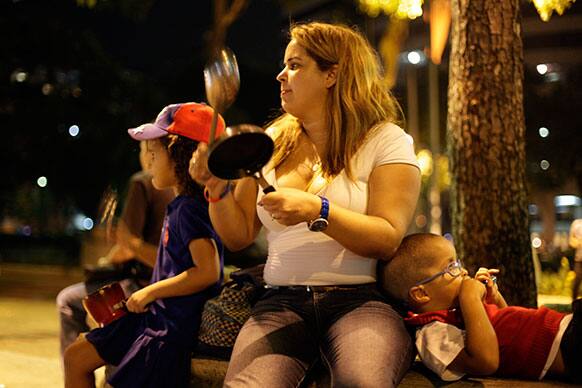 An opposition supporter bangs a pan to protest the official presidential election results in Caracas, Venezuela.