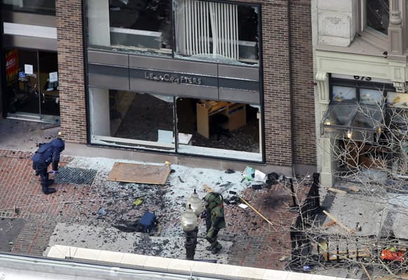 One of the blast sites on Boylston Street near the finish line of the 2013 Boston Marathon is investigated by two people in protective suits in the wake of two blasts in Boston.