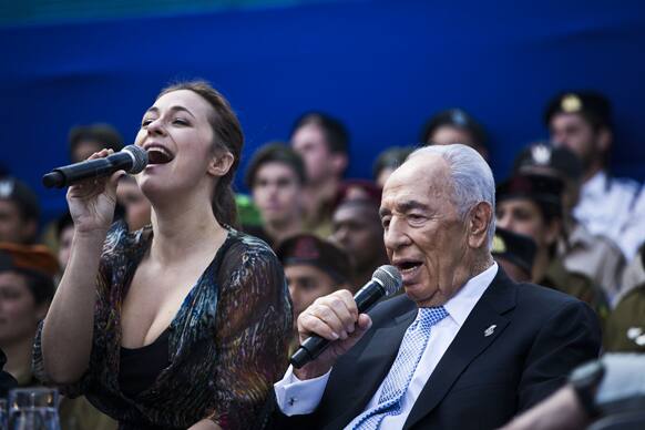 Israeli President Shimon Peres, sings with a singer during Israel`s Independence Day celebration in Jerusalem. Israel is celebrating 65 years of independence with barbeques, air force flyovers, and a bible quiz.