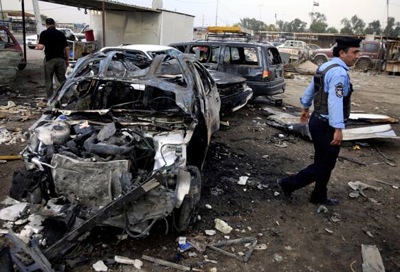 A policeman inspects the aftermath of a car bomb attack at a used cars dealers parking lot in Habibiya neighborhood of eastern Baghdad, Iraq.