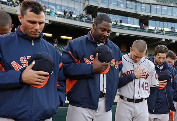 Members of the Houston Astros including Chris Carter, center, observe a moment of silence for the victims involved in an explosion at the Boston Marathon prior to the baseball game against the Oakland Athletics in Oakland, Calif.