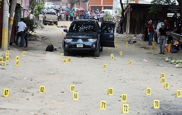 Forensic workers secure the scene after gunmen opened fire on a vehicle, killing a sixteen year-old student, her police bodyguard and three other people who were on the street in the city of Tegucigalpa, Honduras.