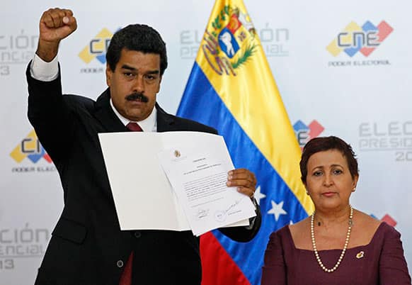 Venezuela`s interim President Nicolas Maduro raises his fist as he holds up the official certificate declaring him winner of the presidential election at the Electoral Council in Caracas, Venezuela.