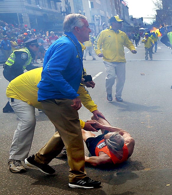 Bill Iffrig, 78, lies on the ground as police officers react to a second explosion at the finish line of the Boston Marathon in Boston.