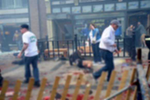 Injured people and debris lie on the sidewalk near the Boston Marathon finish line following an explosion in Boston.