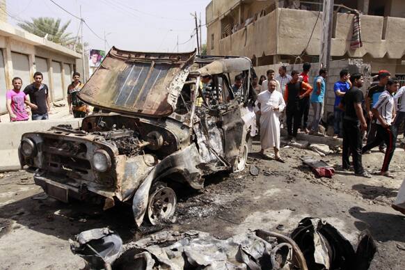 Civilians gather at the scene of a car bomb attack in the east Baghdad neighborhood of Kamaliya, Iraq.